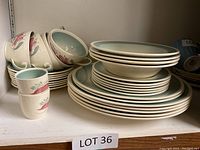 Stack of plates, bowls, and small mugs showing floral china set