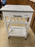 Front view showing granite top, drawer with silver handle, wine rack, and wire basket under the rack.