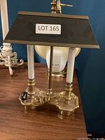 Front view showing the brass base, white glass columns, and dark trapezoidal lampshade with LOT 165 label.