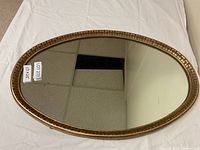 Front view of the oval mirror showing gold decorative frame and mirror surface.