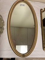 Full view of the oval mirror showing the gold frame and overall shape.