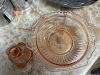 Pink depression glass bowl and candlestick holder on a marble patterned surface