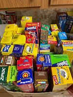 Photo of assorted household food storage and plastic wrap products on a table showing multiple boxes of Glad, Ziplock, Saran Wrap, and related brands.