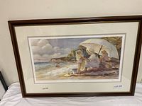 Front view of framed print in wood‐grain frame with double mat showing beach scene with mother and children under umbrella