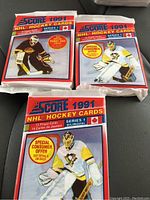 Three sealed wax packs of 1991 Score NHL hockey cards, showing Series 1 and Series 2 designs, featuring hockey goalie images and special consumer offers.
