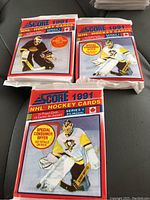 Three sealed 1991 Score NHL hockey card wax packs displayed on a surface. Each pack is labeled Series 1, bilingual, with a goalie image in white and yellow gear.