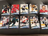 Photo showing 10 Upper Deck Young Guns hockey cards laid out on a black surface with players from various NHL teams in action poses.