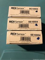 Photo of three boxed REDI-Sensor SE10004 tire pressure monitoring sensors showing model SE10004, frequency 433.92 MHz, barcodes and assembled in Mexico text.