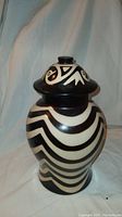 South American earthenware urn with black and white swagged striped design with painted birds on lid, signed on bottom.