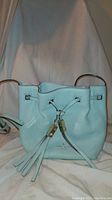 Front view of the white leather Kate Spade handbag showing tassel drawstring and logo.