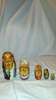 Full view of all five hand painted Russian nesting eggs arranged in size order on a white cloth background.