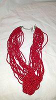 Multi-strand red coral mini bead necklace laid flat showing multiple strands and chain clasp