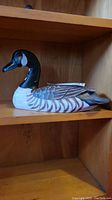 Side view of the carved wooden duck showing detailed paint and feather texture.