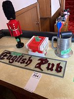 British palace guard figurine, English Pub sign, coasters, and metal tankard with darts on table