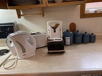 Full view of all items on countertop showing 1.7L Salton kettle, Simplicity two-slice toaster, bagel cutter, and blue ceramic canisters