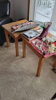 Two matching wood side tables side by side with various items on top, showing overall shape and size.