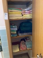 Shelves containing the collection of folded bath towels, hand towels, facecloths in various colors including yellow, pink and green.