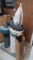 Front view of Jet DC-650 dust collector with cloth filter bag, motor housing, flexible hose and cardboard box with coiled hose