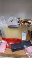 Gray plastic tote holding bubble wrap, rolled brown packing paper, and caliper cases on a flat surface.