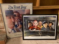 Two framed prints side by side; left is Seattle Rep poster 'The Front Page', right is 'The Artist Carpool' print with caricatured artists in a Mercedes.
