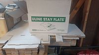 Stack of flat packed Uline Stay Flats shipping boxes with label visible