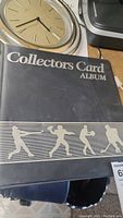 Dark blue Collector's Card Album binder with silver sports players silhouettes on cover.