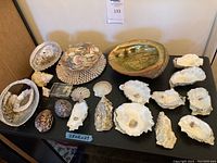 Photo showing the full collection with various seashell types arranged on black surface including abalone shell, oyster shells, scallops, and other small shells.