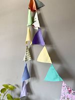 Long view of the bunting hanging against a wall showing the triangular flags in multiple colors and a floral pattern.