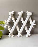 Full view of the white wooden expandable peg rack displayed in expanded position showing 10 pegs.