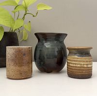 Set of three pottery vases arranged in a row showing size and glaze differences.