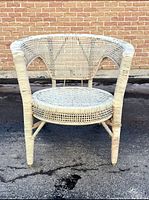 Full front view of the white wicker chair showing the woven seat and armrests