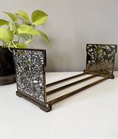 View of book holder from side showing brass filigree end panels and connecting rods.