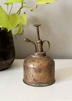 Photo of vintage brass flower spritzer showing full item with patina and aged wear.