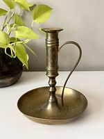 Side view of vintage brass large chamber style candlestick holder showing handle and base