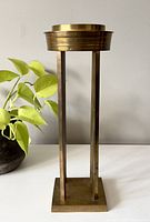 Front view of vintage tall solid brass candle holder showing square base, four vertical rods, and round top with recessed candle holder