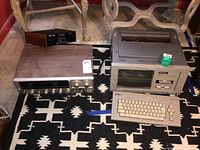 Wide shot showing both the Sansui stereo receiver and Smith Corona word processor together on a patterned rug.