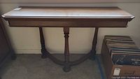 Full front view of the vintage wooden sofa table with rectangular top and carved legs.