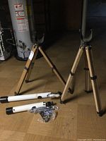 Two white telescope tubes laid on the floor with two wooden tripod stands behind them, mounting accessories in plastic bags in front.