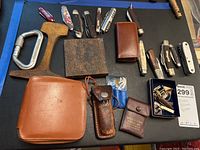 Top view of entire lot showing pocket knives, leather cases, and metal tools.