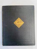Front cover of the book showing black leather cover with embossed border and gold diamond emblem.