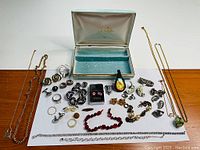 Full view of jewelry box with assorted jewelry pieces displayed outside, including necklaces, earrings, rings, and pendants.
