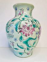 Full side view of the vase showing floral hand-painted decoration with pink flowers and green leaves on white background.