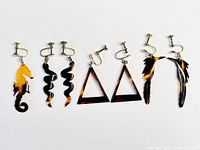 Photo of six pairs of vintage clip-on earrings in various animal and geometric shapes made of tortoiseshell-patterned celluloid.