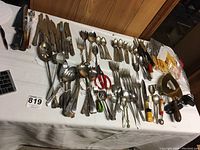 Wide view of assorted flatware spread on a table including knives, forks, spoons, and various serving utensils.