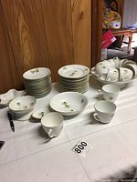 Partial set of yellow floral china including stacked plates, bowls, cups, and other items arranged on a table