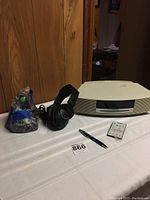 Bose Wave unit, wireless headphones with charging base, and remote control on table