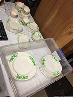Photo showing various stacked plates and cups with green shamrock pattern on white porcelain.