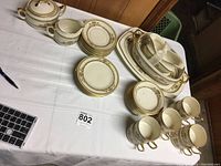 Full set on display including plates stacked, cups, sugar bowl, creamer, gravy boat with underplate, oval server, small and large platters arranged on table.
