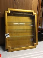 Front view of the rectangular glass front display case showing the frame detail, glass shelves, and overall structure.