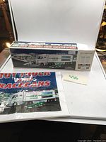 Photo of the Hess truck and race cars box with original Hess branded bag behind them.